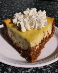 Slice of creamy lemon cheesecake with lemon curd topping on a white plate