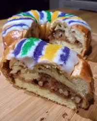 Traditional king cake with purple green and gold sugar on a white platter