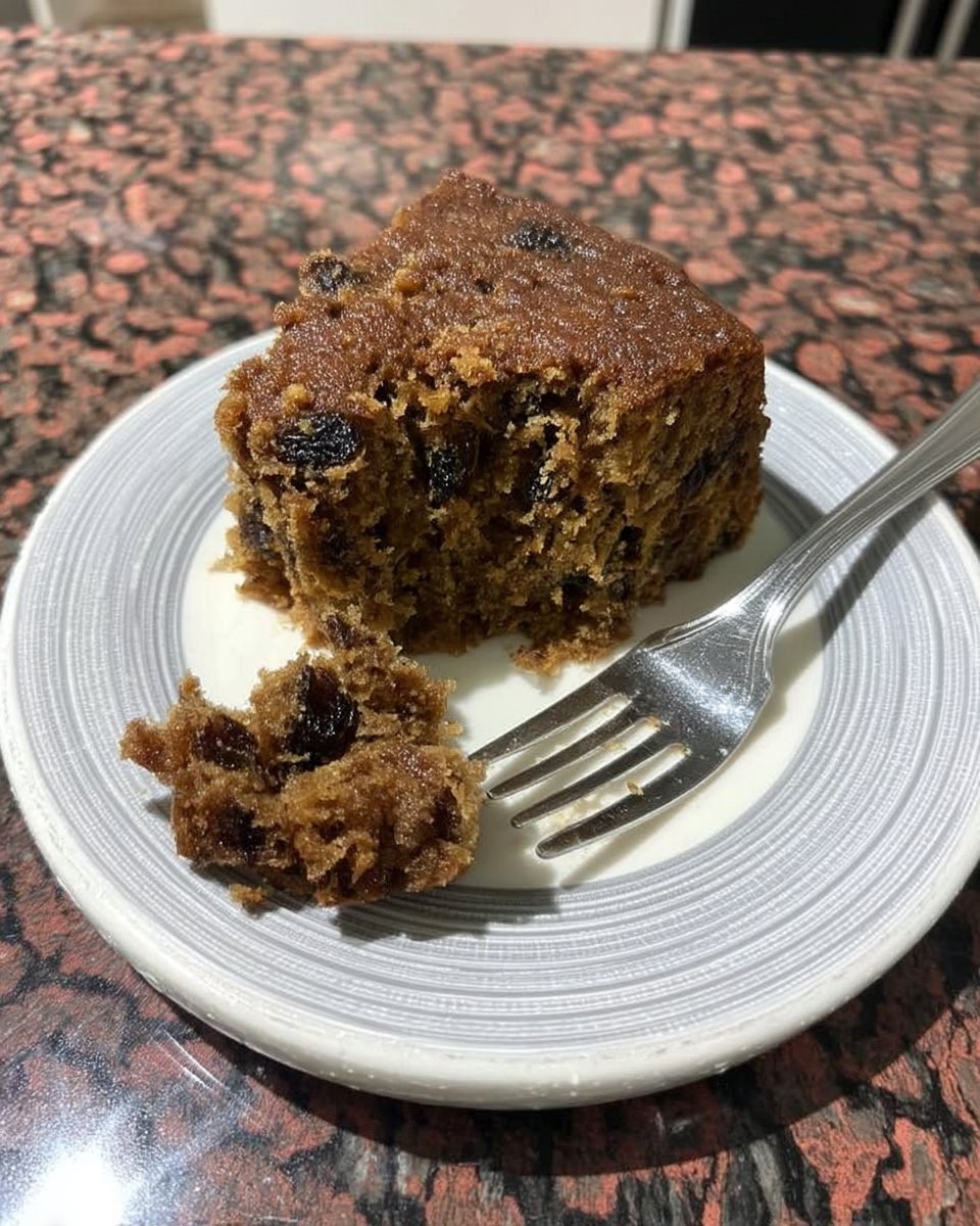 A loaf of rich fruitcake sitting on a cooling rack