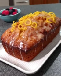 Sliced lemon drizzle cake on a wire rack with fresh lemon zest