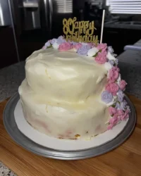 A beautiful floral cake decorated with colorful buttercream flowers on a white stand.