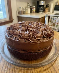 A beautifully decorated chocolate cake with smooth frosting and chocolate shards