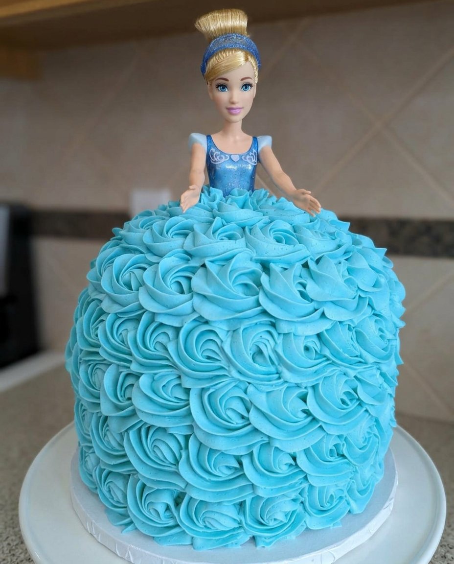 A completed Cinderella doll cake with blue frosting rosettes