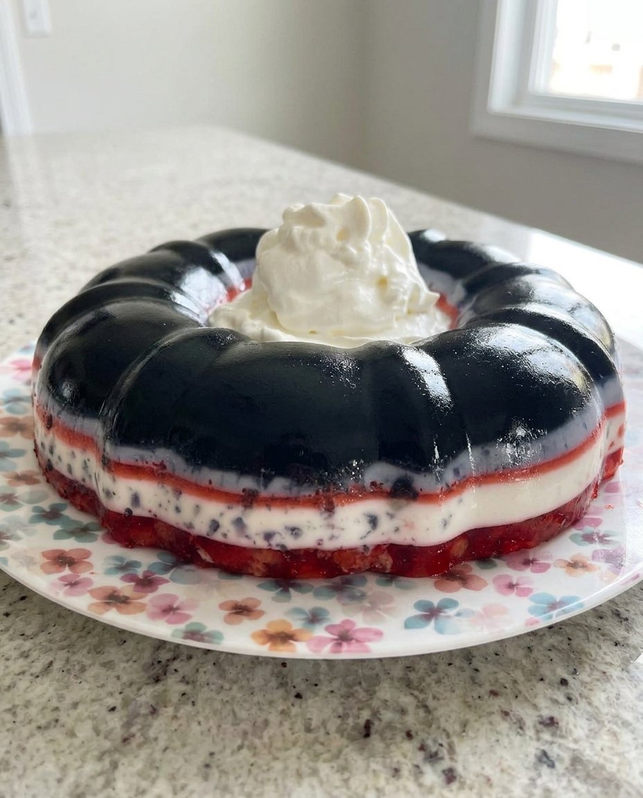 A shimmering red and white layered strawberry jello cake in a bundt pan shape
