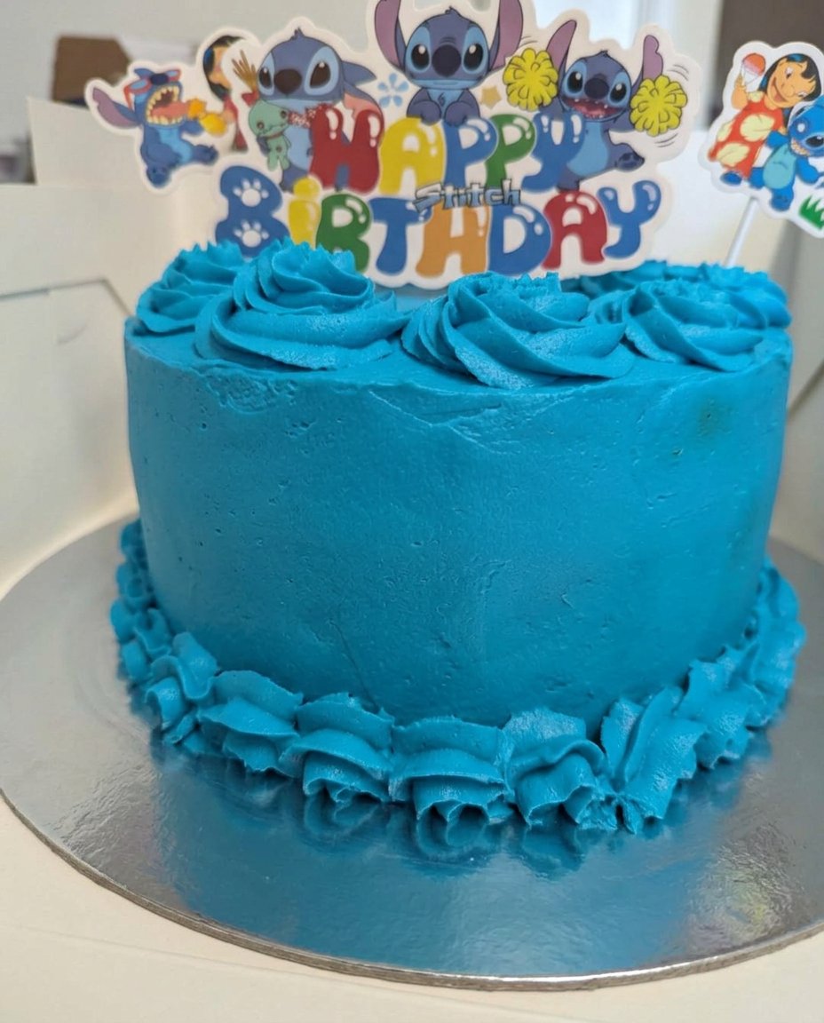 Top view of a chocolate cake with buttercream swirls and fresh cherries