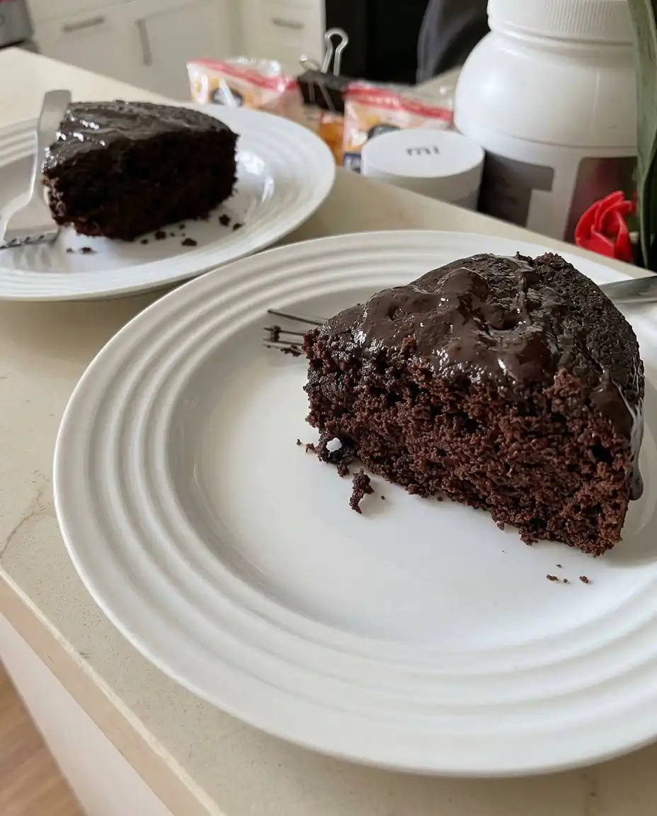 A person spreading chocolate frosting onto a cake layer with an offset spatula