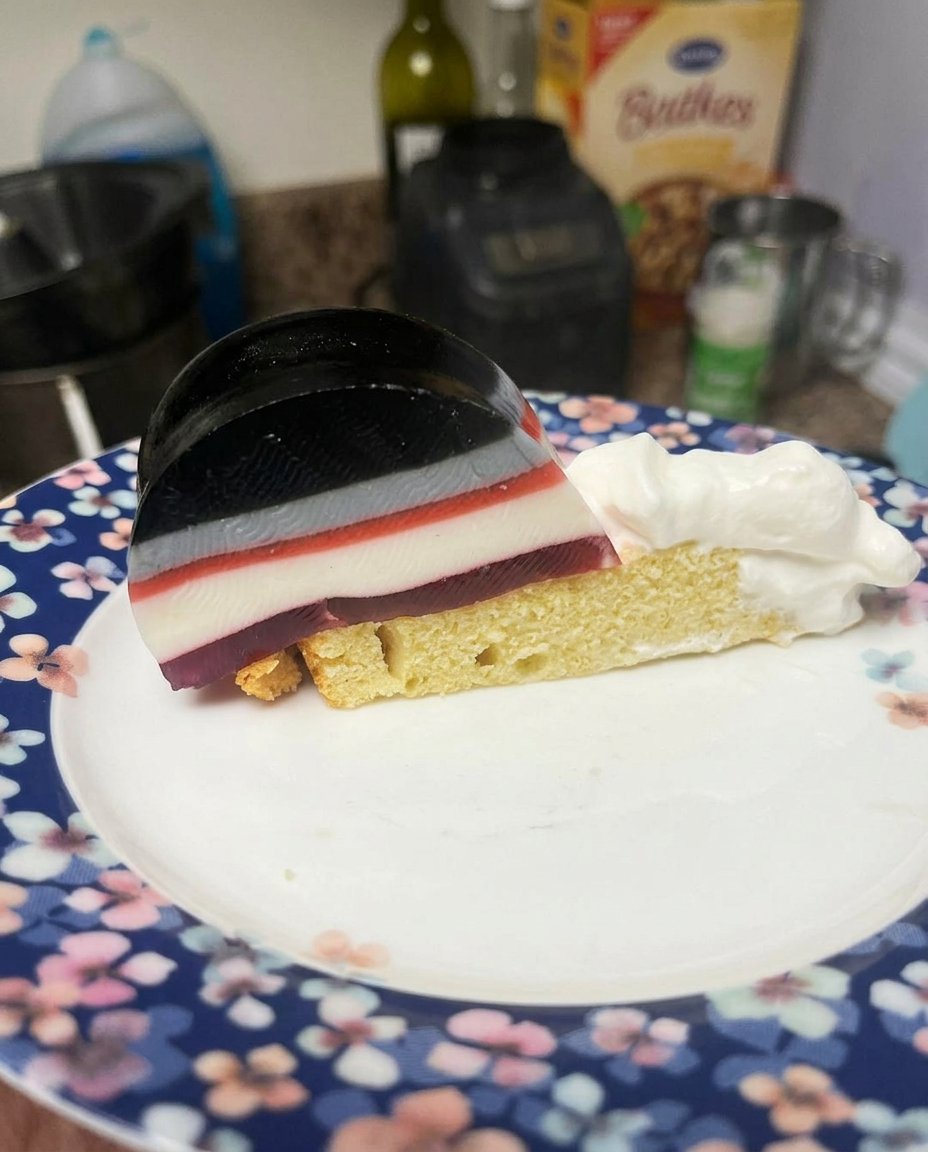 A bundt pan filled with red jello and strawberry slices sitting on a refrigerator shelf