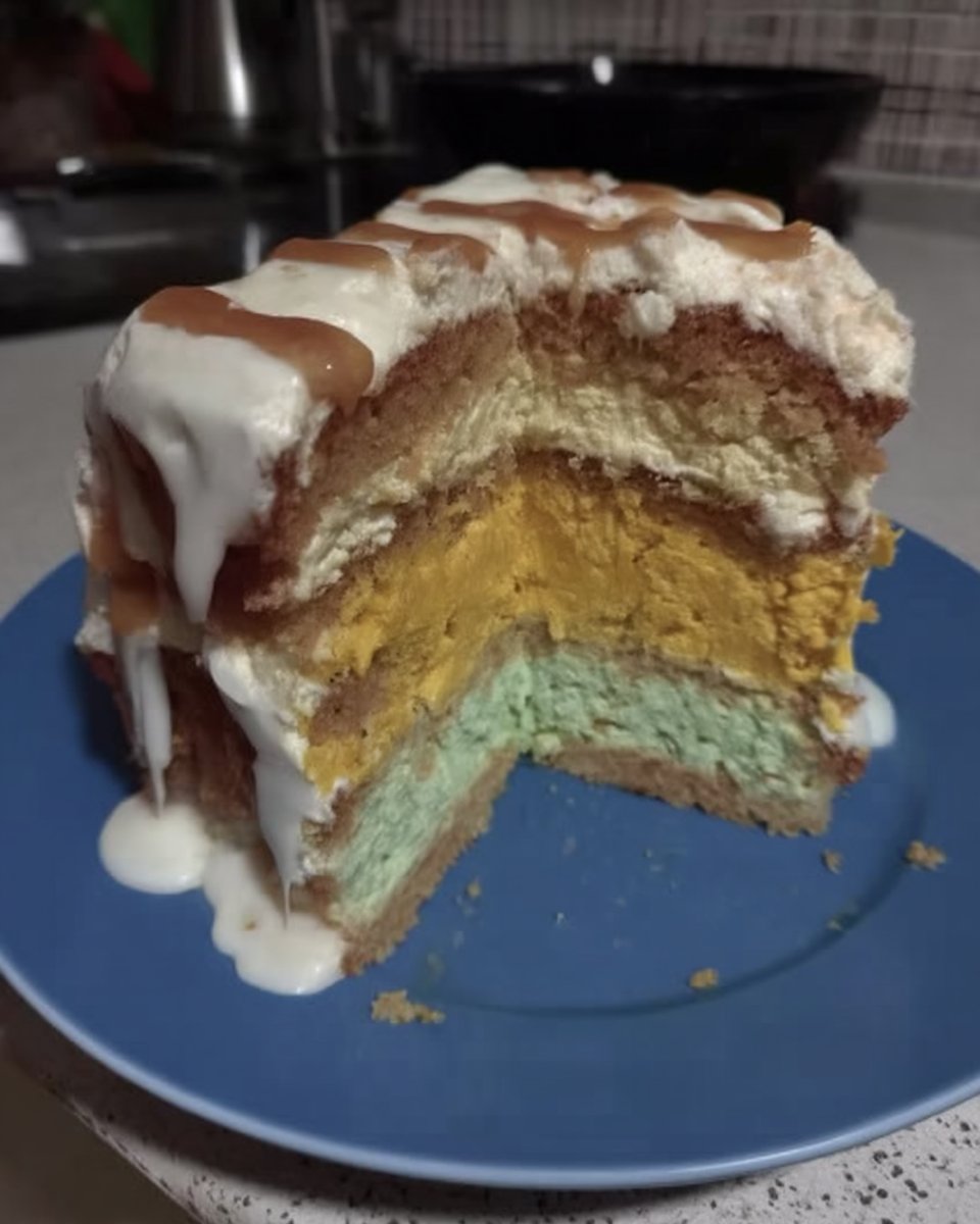 Three bowls of colorful cake batter in yellow orange and green