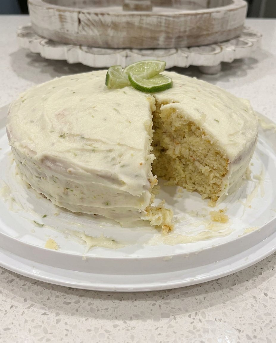 A thick slice of Key Lime Cake with green cream cheese frosting on a white plate