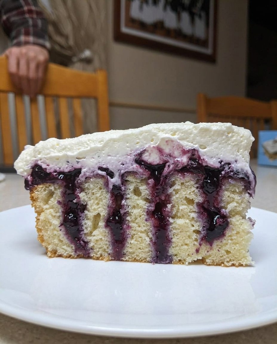 Using the end of a wooden spoon to poke holes in a warm lemon cake.