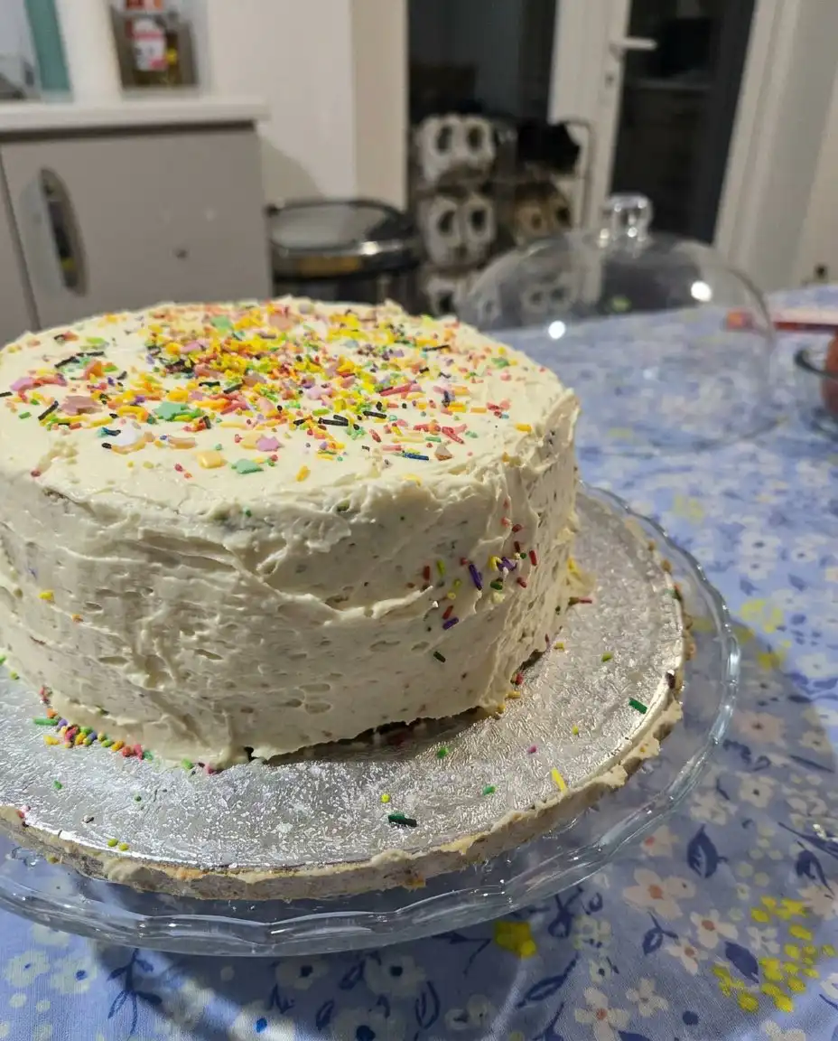 A slice of vanilla cake with chocolate frosting on a white plate with a fork
