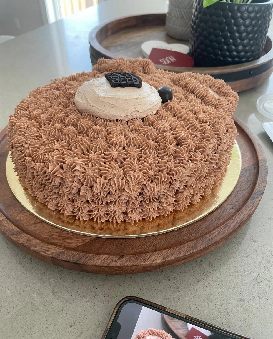 A homemade chocolate bear cake decorated with buttercream stars and cookie ears.