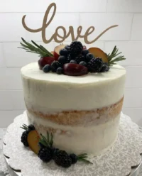 A simple nude cake sitting on a white cake stand