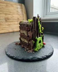 A simple homemade Shrek cake covered in green marzipan with a smiling face.