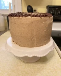 A golden brown small cake sitting in a parchment lined baking pan on a wooden table