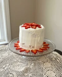 A pink strawberry cake on a kitchen counter