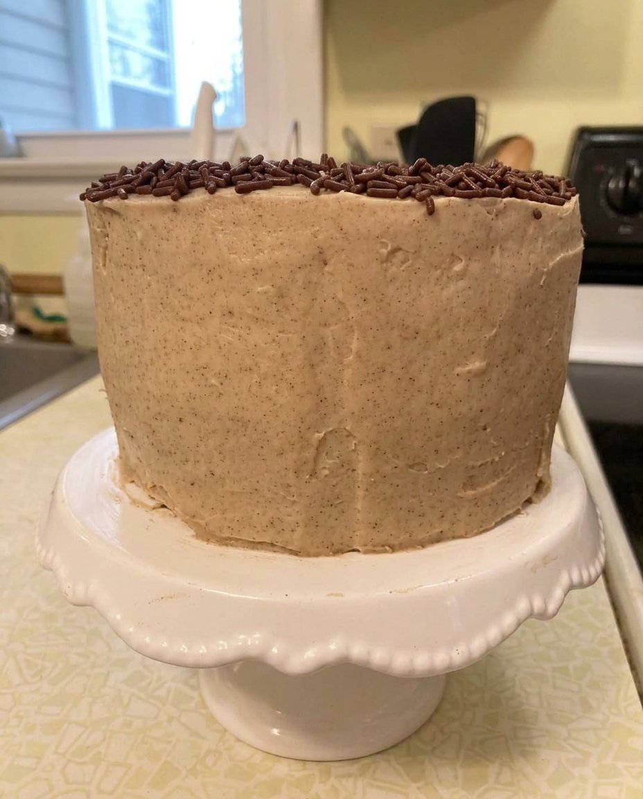 A single thick slice of small cake served on a white ceramic plate next to a cup of black coffee