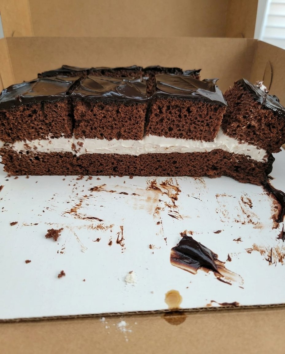 A slice of square chocolate cake served with fresh berries and whipped cream
