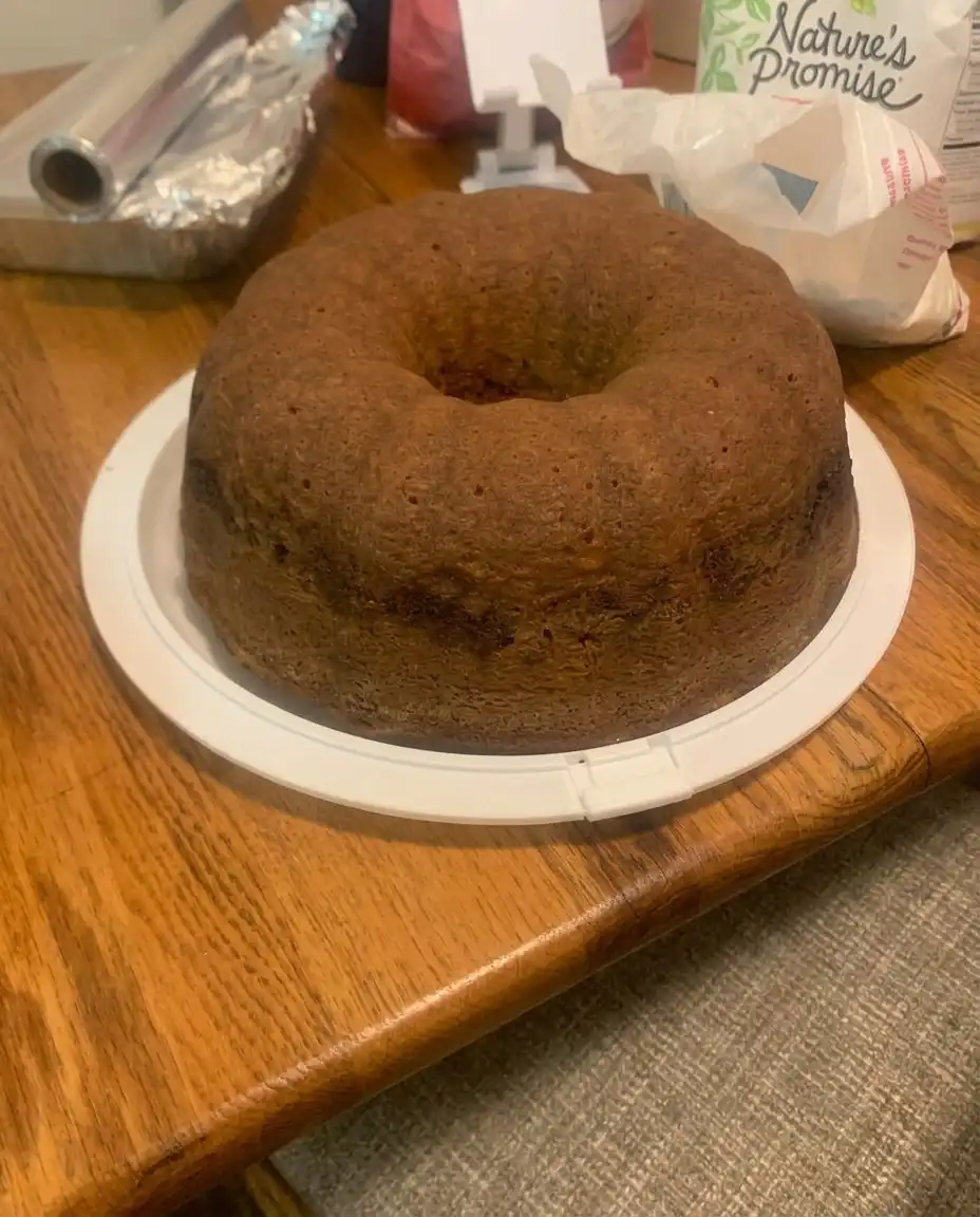 Pouring yellow cake batter over the brown sugar streusel layer in a greased bundt pan