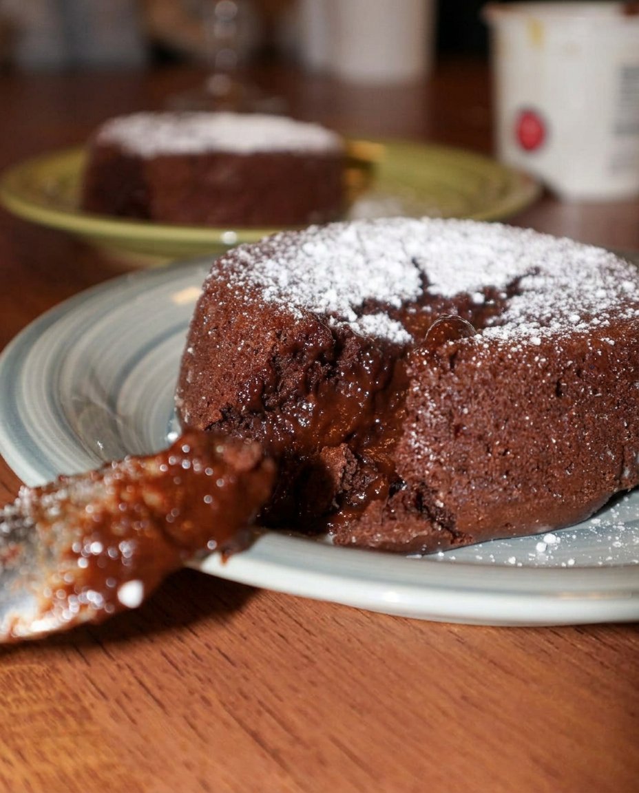 A chocolate lava cake served with a scoop of vanilla ice cream and a fresh strawberry