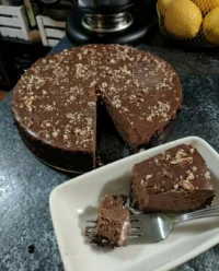 A close up of a slice of chocolate truffle cake with a smooth glaze