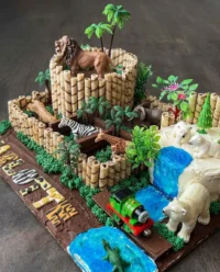 A colorful animal cake with various zoo exhibits and fondant letters