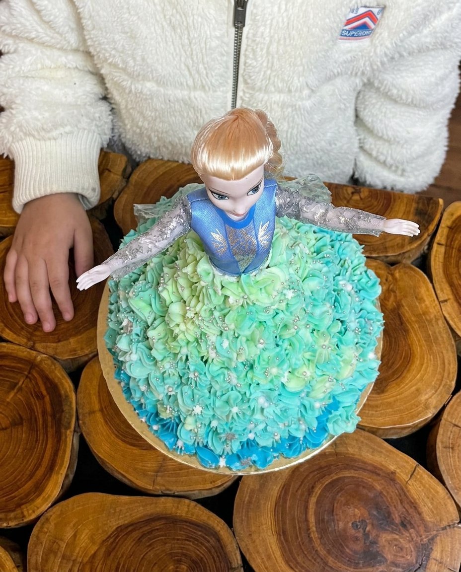 A completed Elsa doll cake with light blue icing and snowflake decorations
