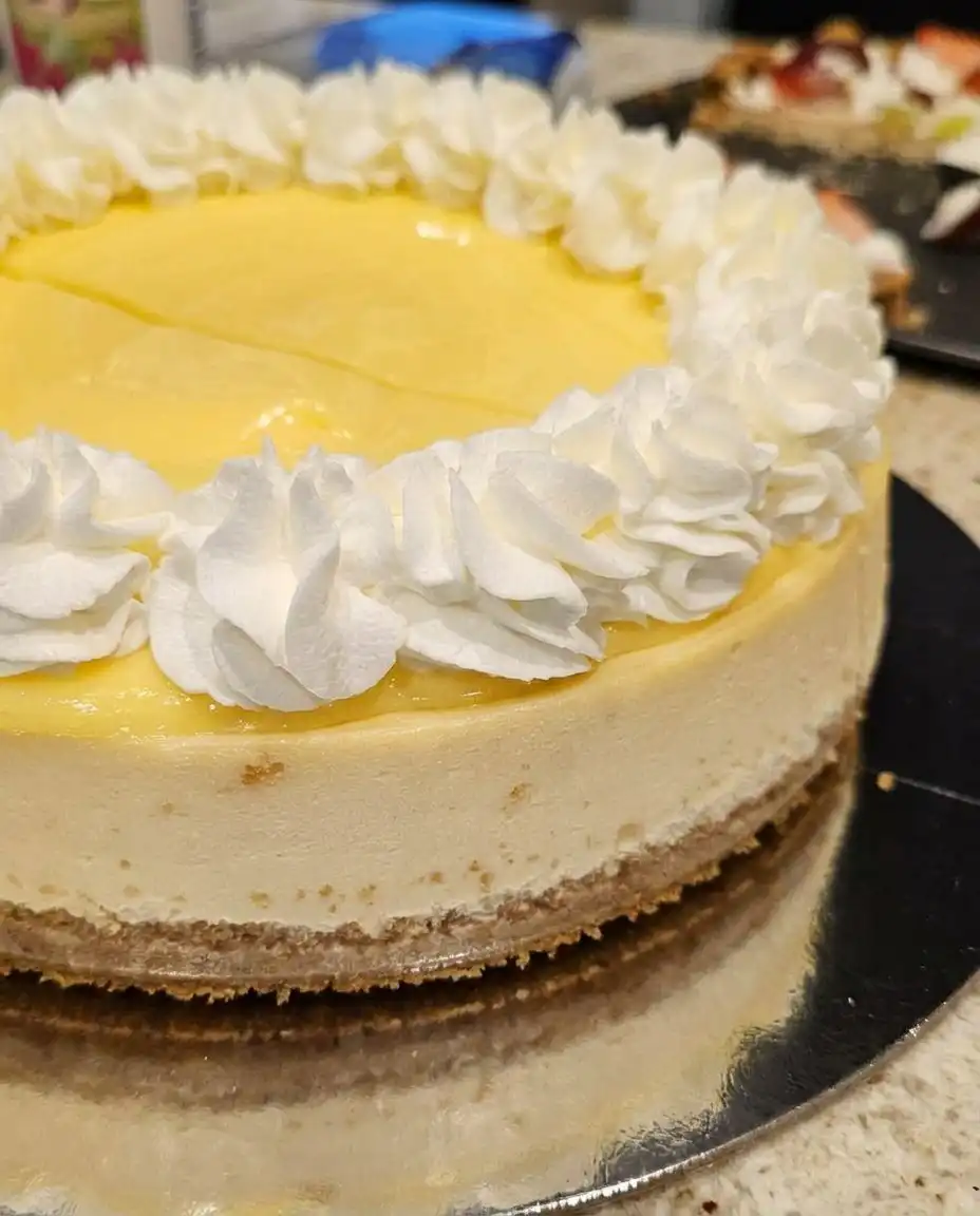 A single slice of lemon cheesecake on a white plate with a fork