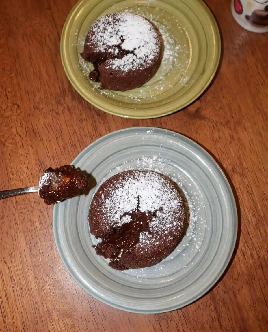 Chocolate Lava Cake 2 10 A close up of a chocolate lava cake with a molten ganache center flowing out on a white plate