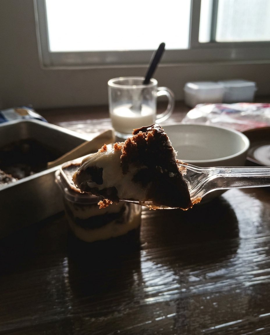 Hand piping white frosting onto a cake layer inside a glass jar