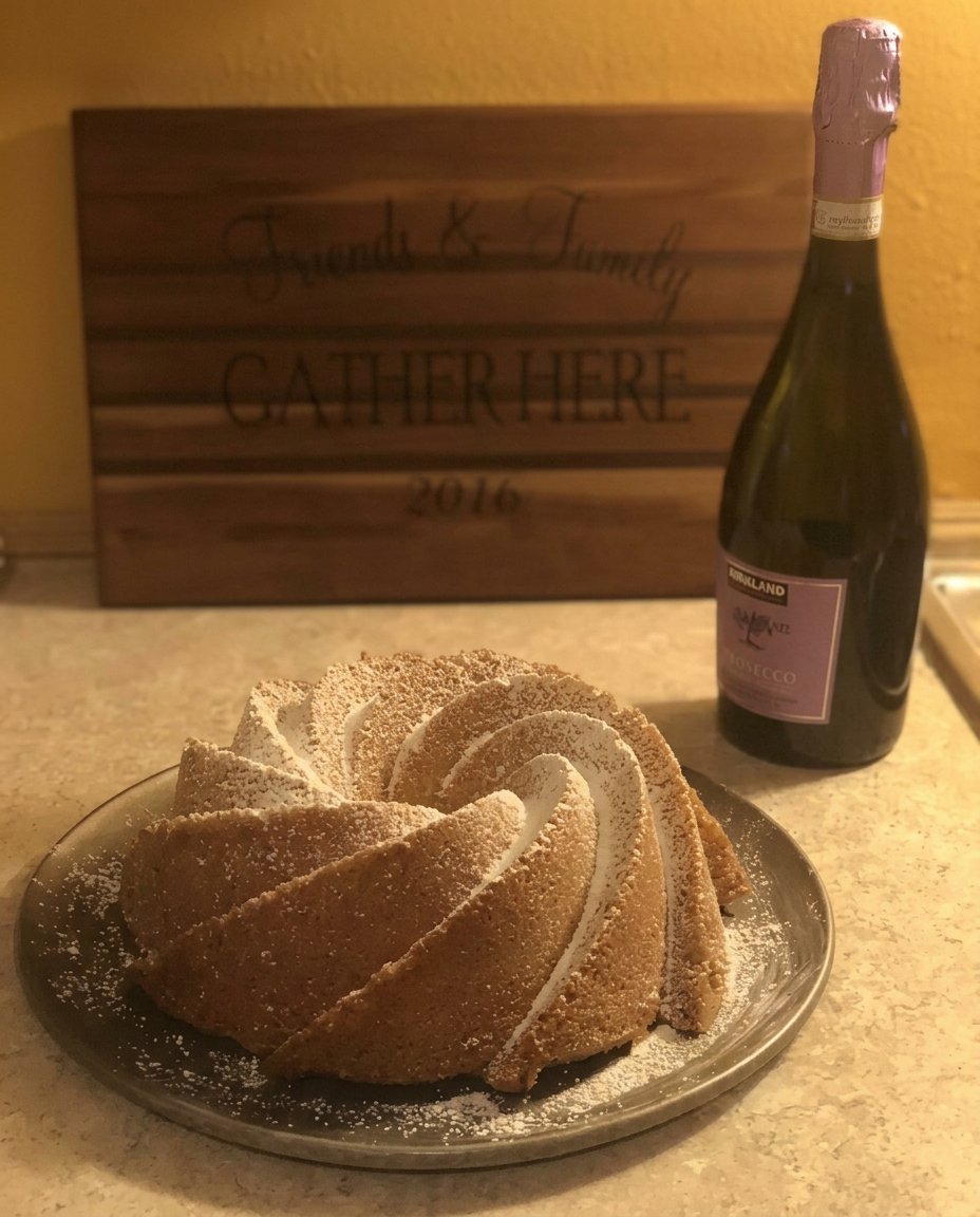 Close up of someone sifting powdered sugar into a glass bowl for a smooth cake glaze