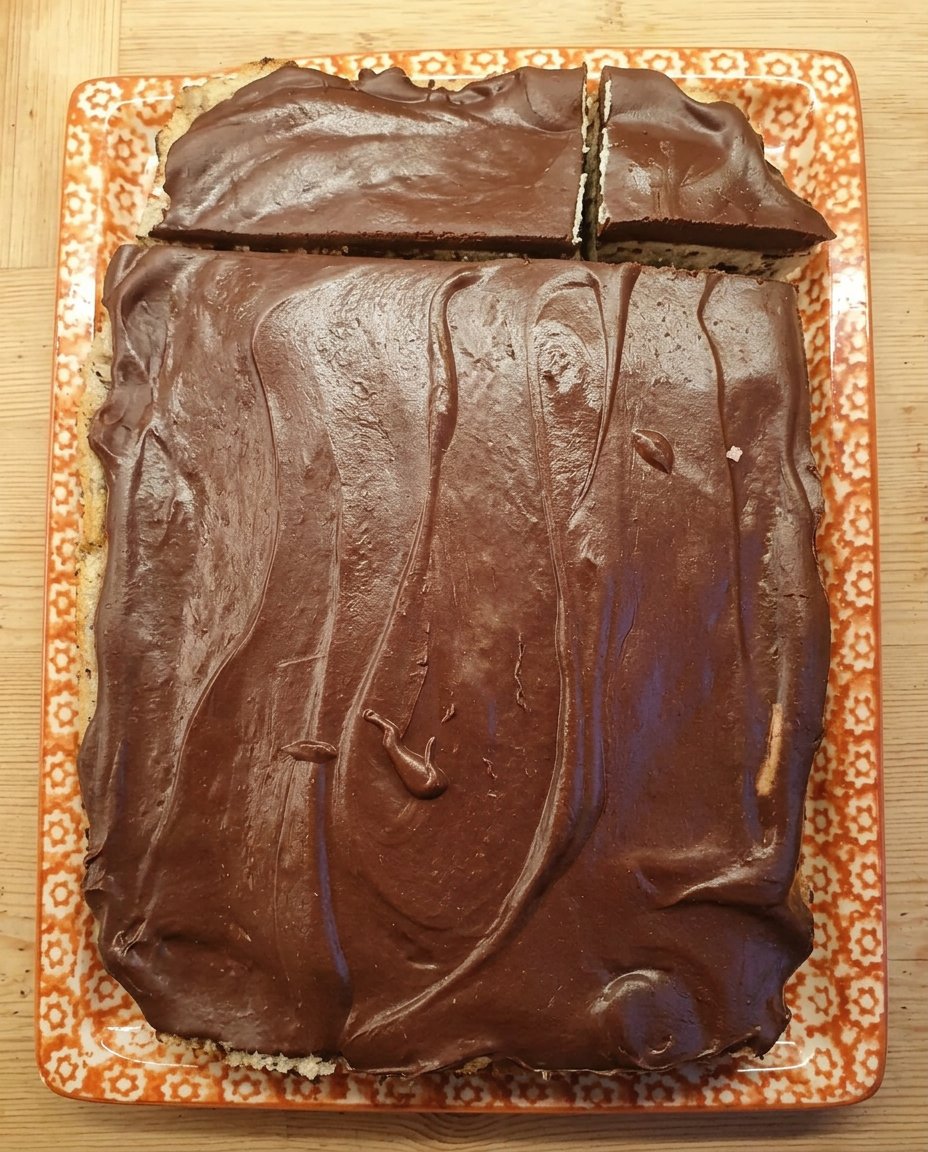 A moist chocolate cake covered in smooth dark chocolate ganache on a white plate