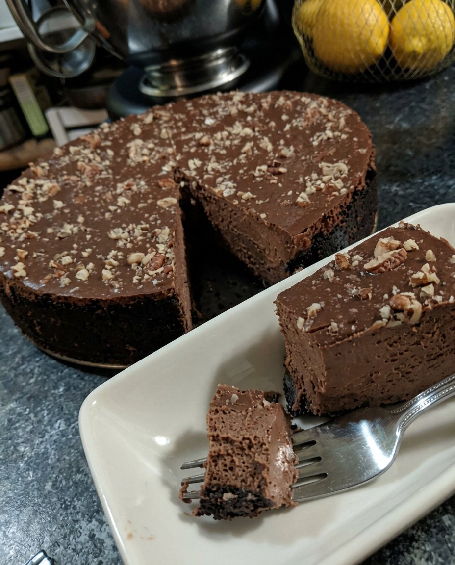A slice of chocolate truffle cake served on a white plate with a fork