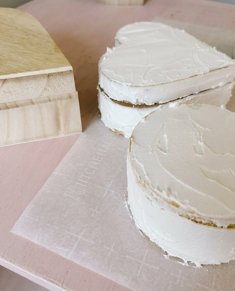Smoothing pink strawberry frosting onto a store-bought sponge cake
