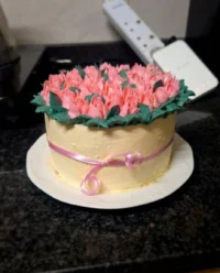 A beautiful six inch cake decorated with piped icing tulips in purple and ivory