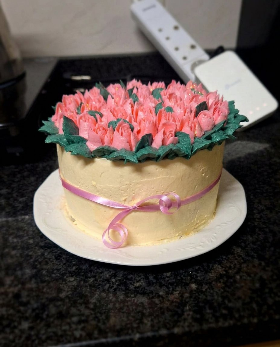 A beautiful six inch cake decorated with piped icing tulips in purple and ivory