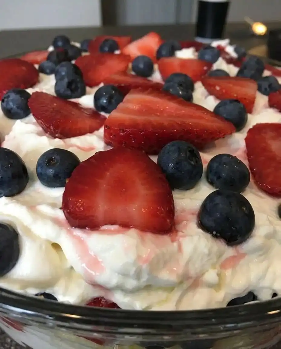 Layering fresh strawberries against the side of a glass trifle bowl over cake cubes and white pudding