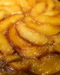 A slice of golden bourbon peach upside down cake on a white plate