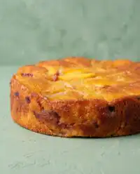 A close up shot of a Brown Butter Fresh Peach Cake with a thick layer of golden crumb topping.