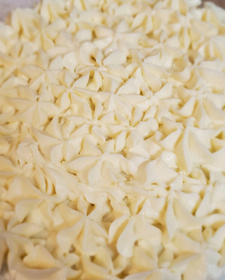 A hand brushing lemon syrup onto a sponge cake layer