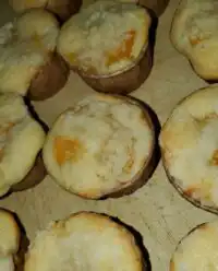 A tray of golden brown canned peach cobbler muffins with streusel topping