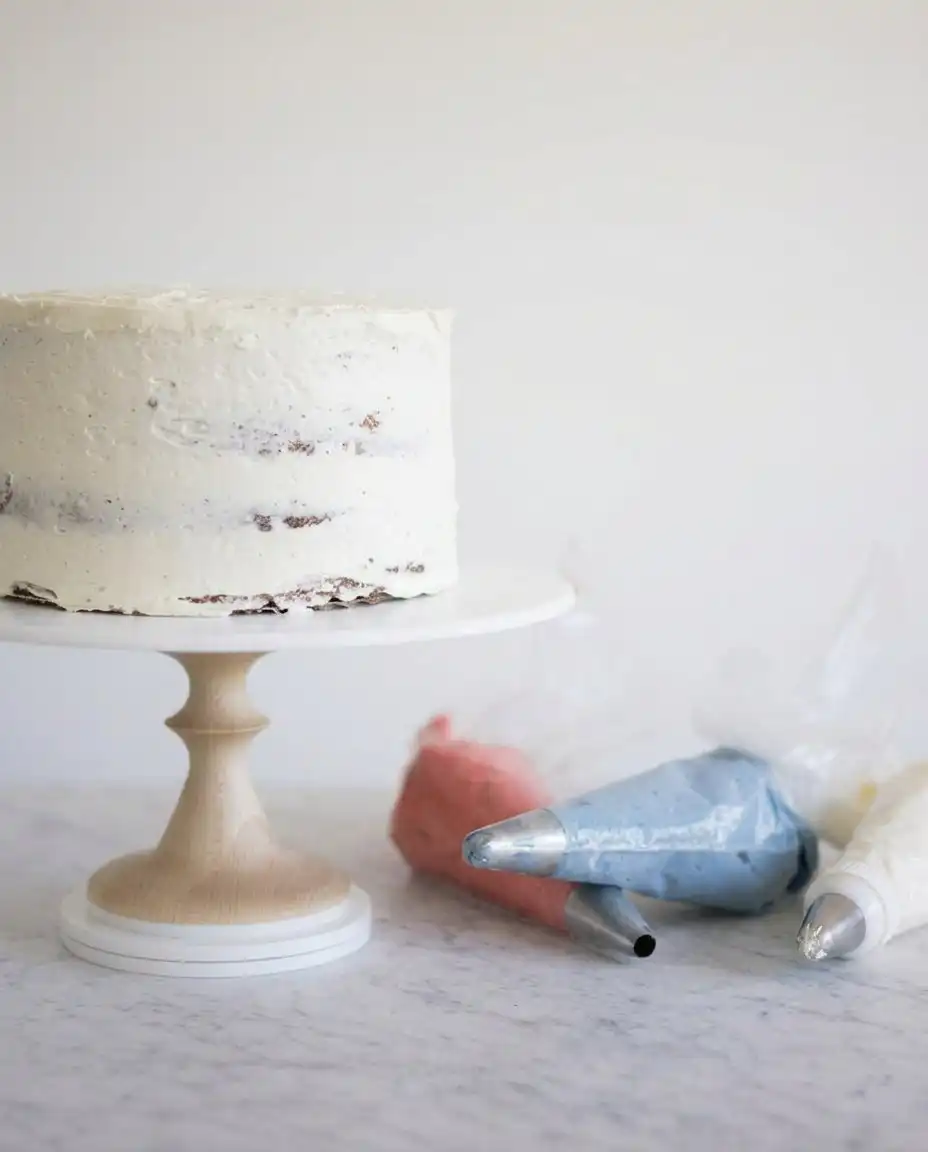 Close up of a spatula smearing buttercream dots on a cake.