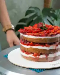 A close up view of three soft layers of Strawberry Vanilla Cake with whipped cream and berries.