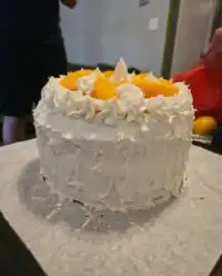 A stunning three layer peaches and cream cake topped with fresh fruit and whipped cream