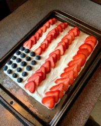 A decorated gluten free American flag cake resting on a summer picnic table