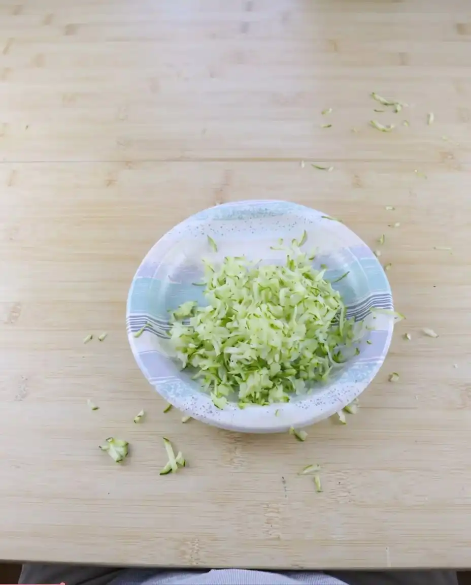 Shredded zucchini and diced apples next to flour and spices for apple zucchini bread.