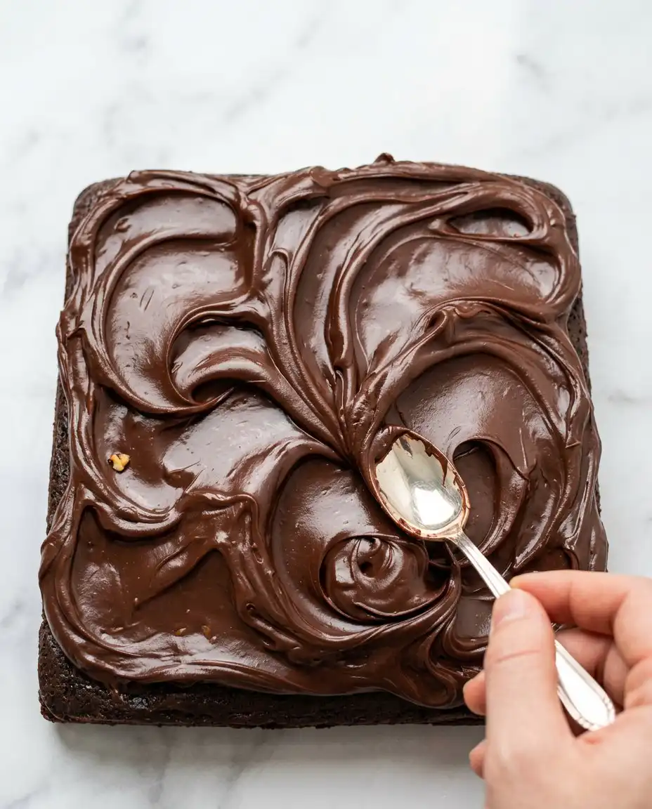 A wooden spoon stirring dark batter for a Vegan Chocolate Zucchini Cake in a large ceramic bowl.