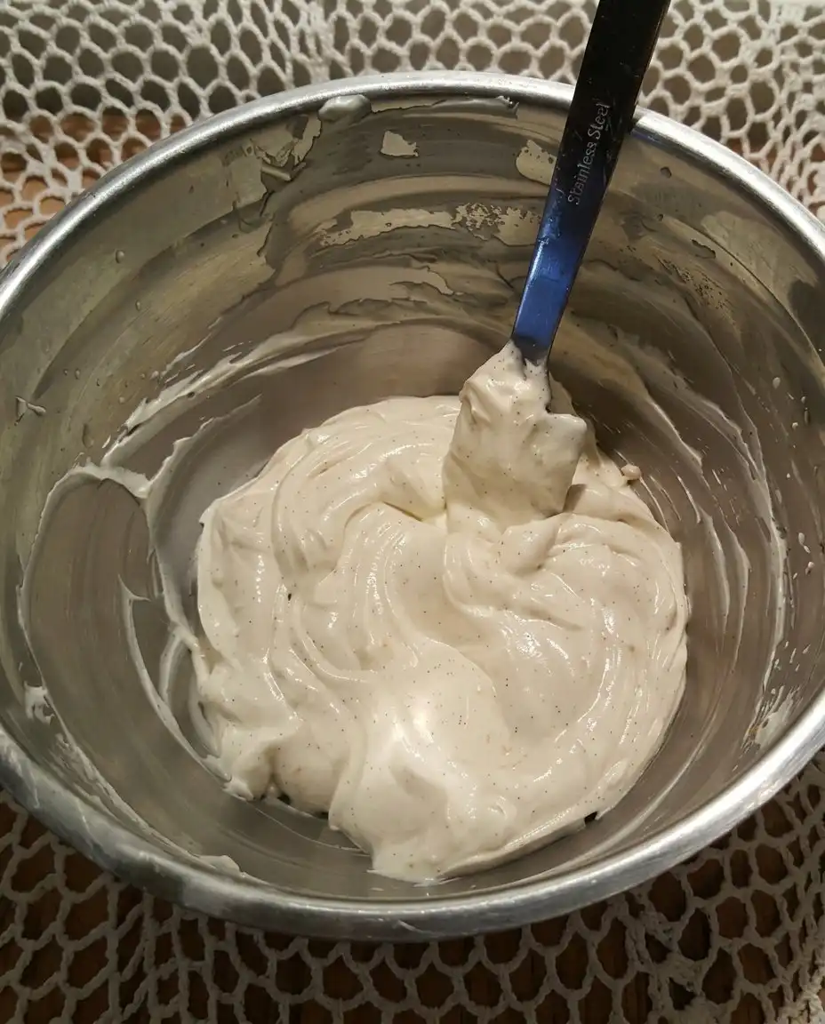 A close up of a hand folding whipped topping into a cream cheese base.