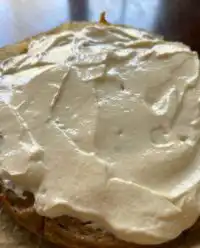 A thick slice of Moist Zucchini Banana Cake with creamy maple frosting on a white plate.