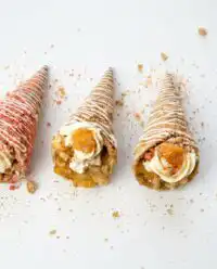 Delicious peach cobbler cheesecake cones served in crunchy waffle bowls